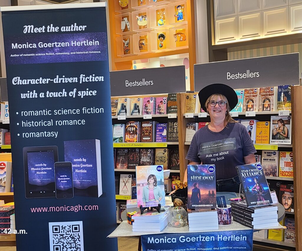 Monica in a cowboy hat at Indigo with her book table.
